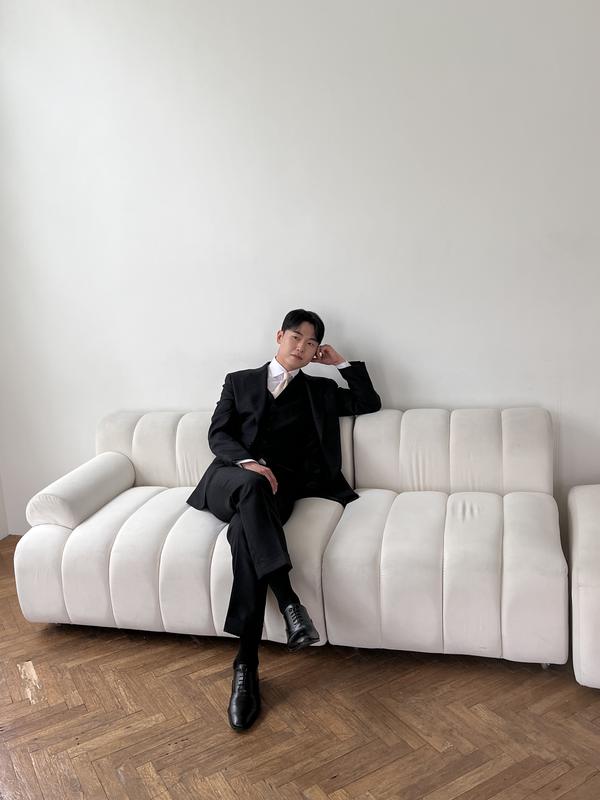 블랙 쓰리피스 수트를 입고 소파에 앉은 모델